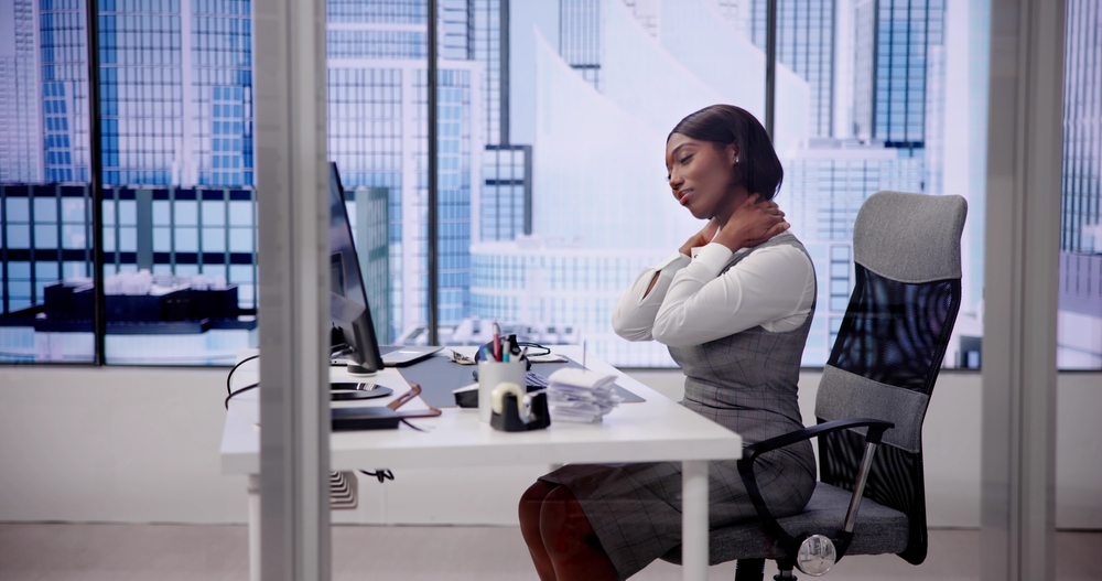 A woman is experiencing neck strain because of of her desk furniture